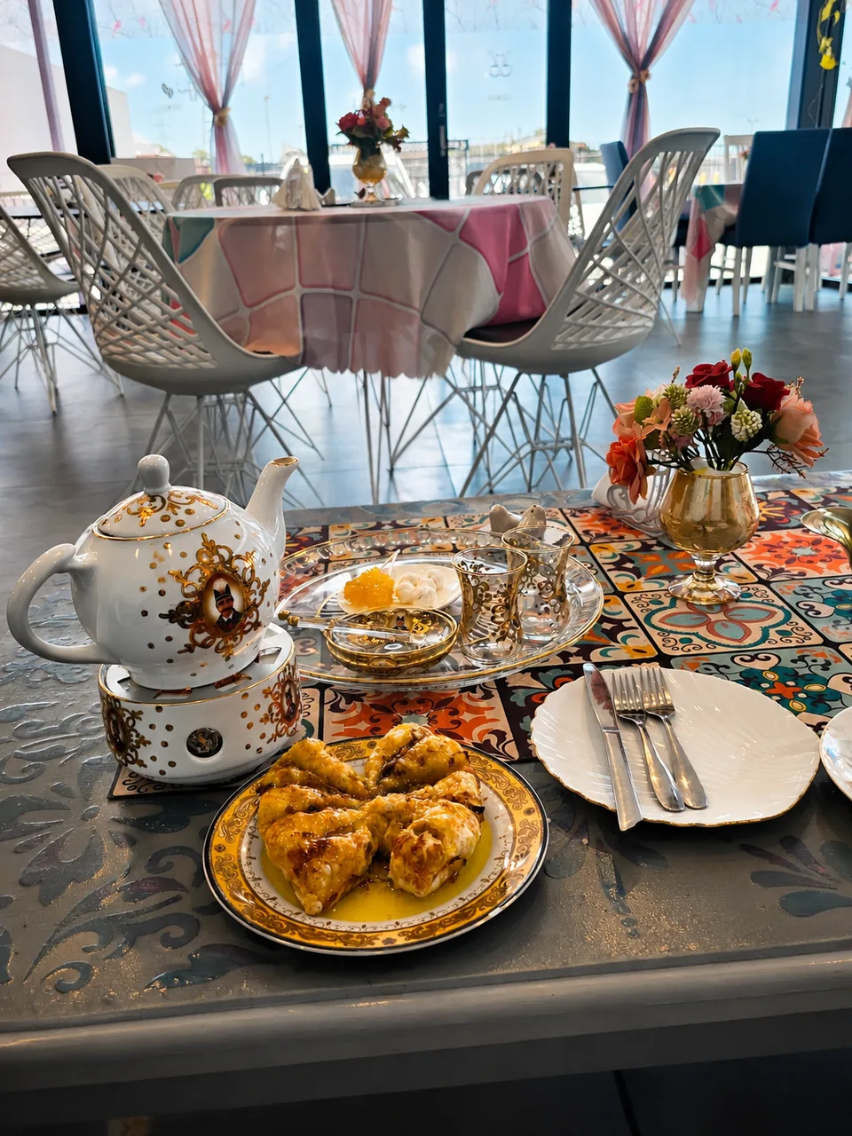 Persian tea service and pastries at a colourful café table